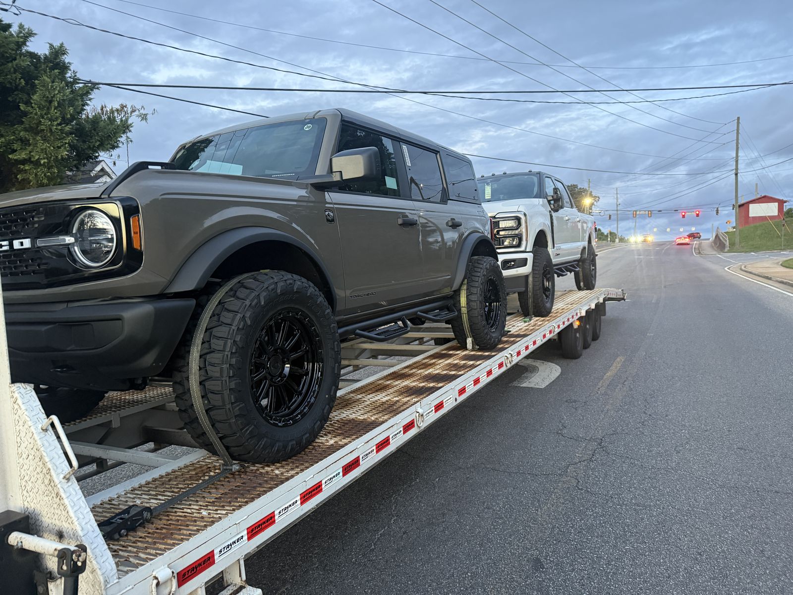 Ford Bronco and white Ford Super Duty loaded on the gooseneck trailer at dusk